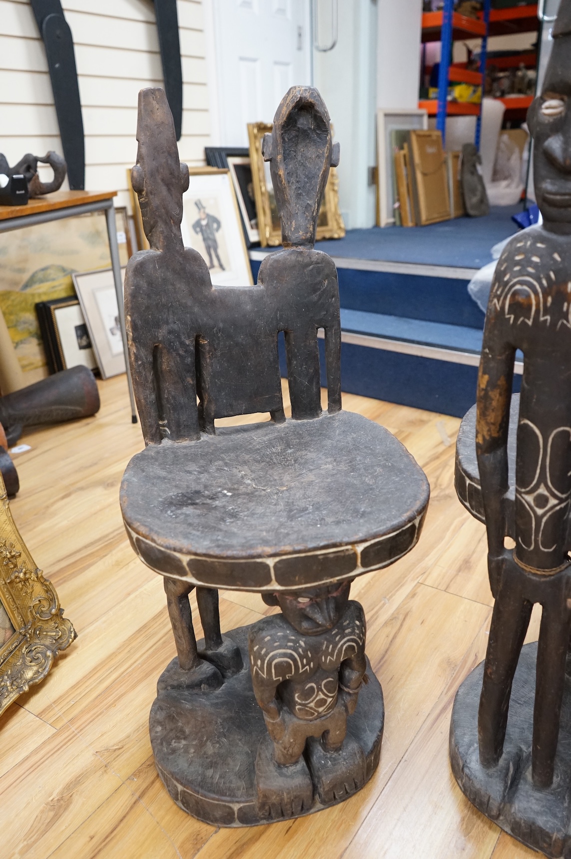 Papua New Guinea Sepik River, a near pair of ‘ceremonial’ figural chairs, each carved from a single section of a tree trunk with integral male and female backs and an castor figure front support with cowrie shell eyes. H